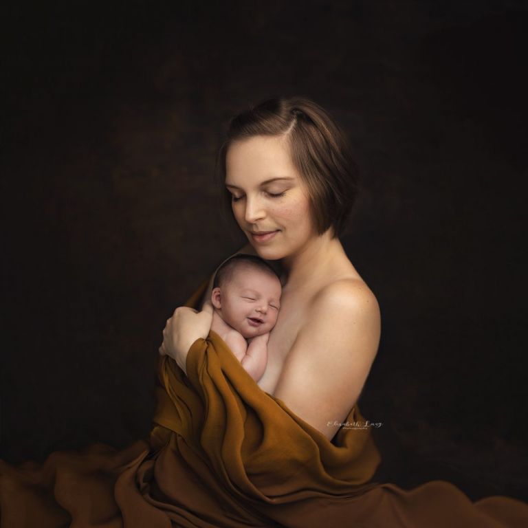 A mother and her baby draped in flowing fabric for her baby photos